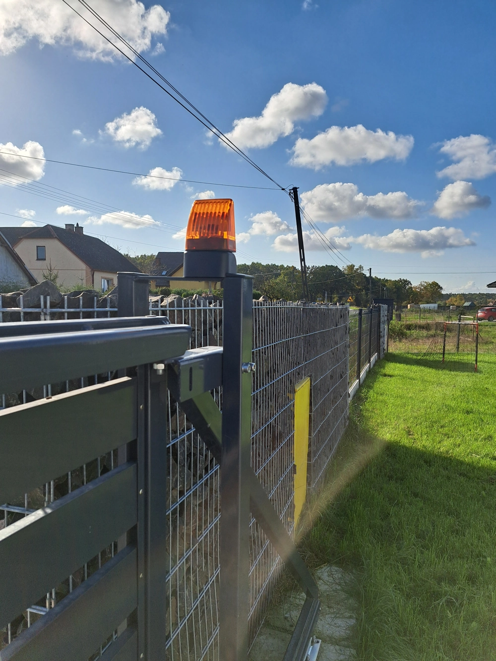 Stalowa automatyczna brama przesuwna z lampą ostrzegawczą