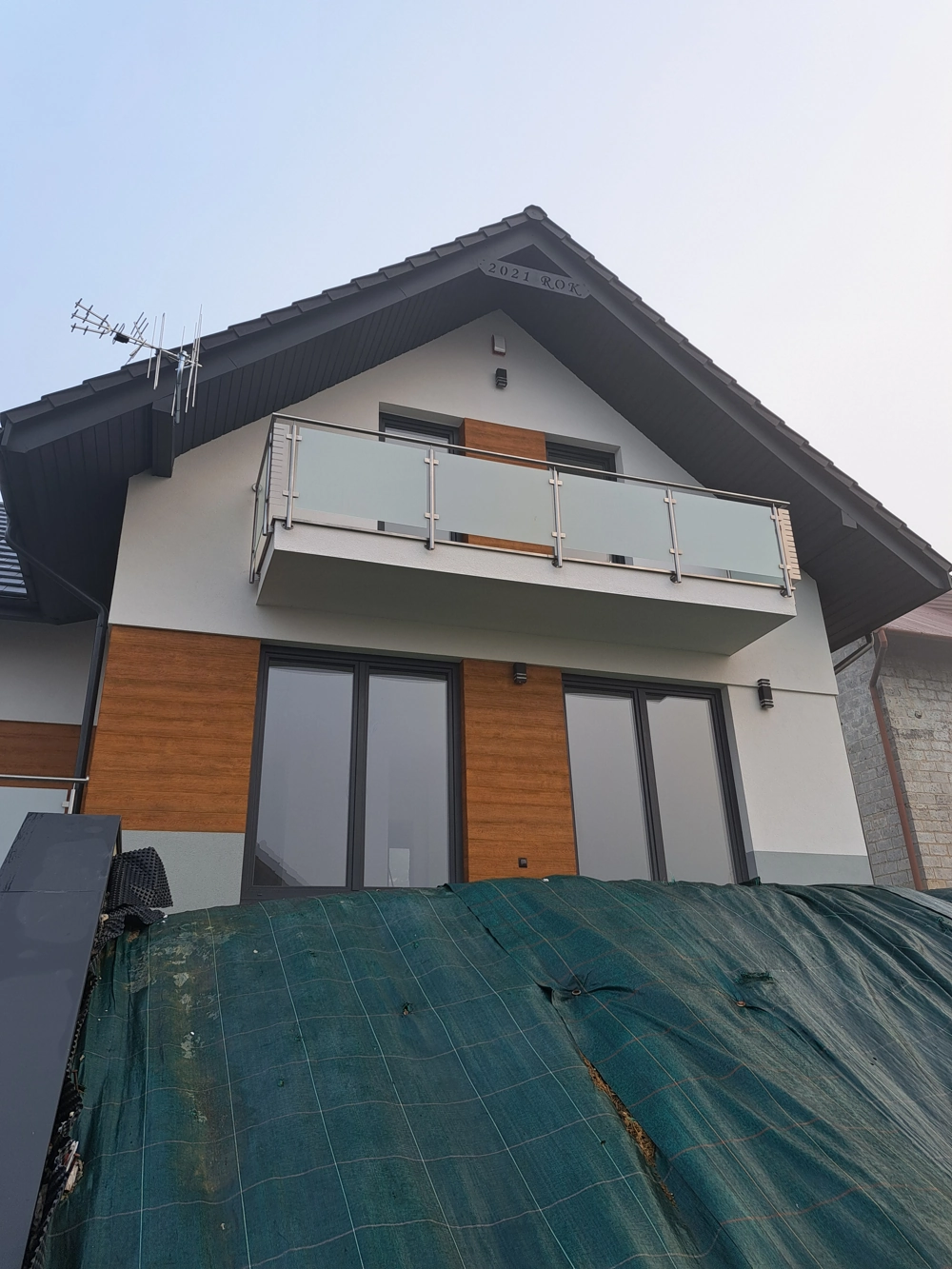 Nowoczesne balustrady balkonowe ze szkła i stali na elewacji domu z drewnianymi akcentami