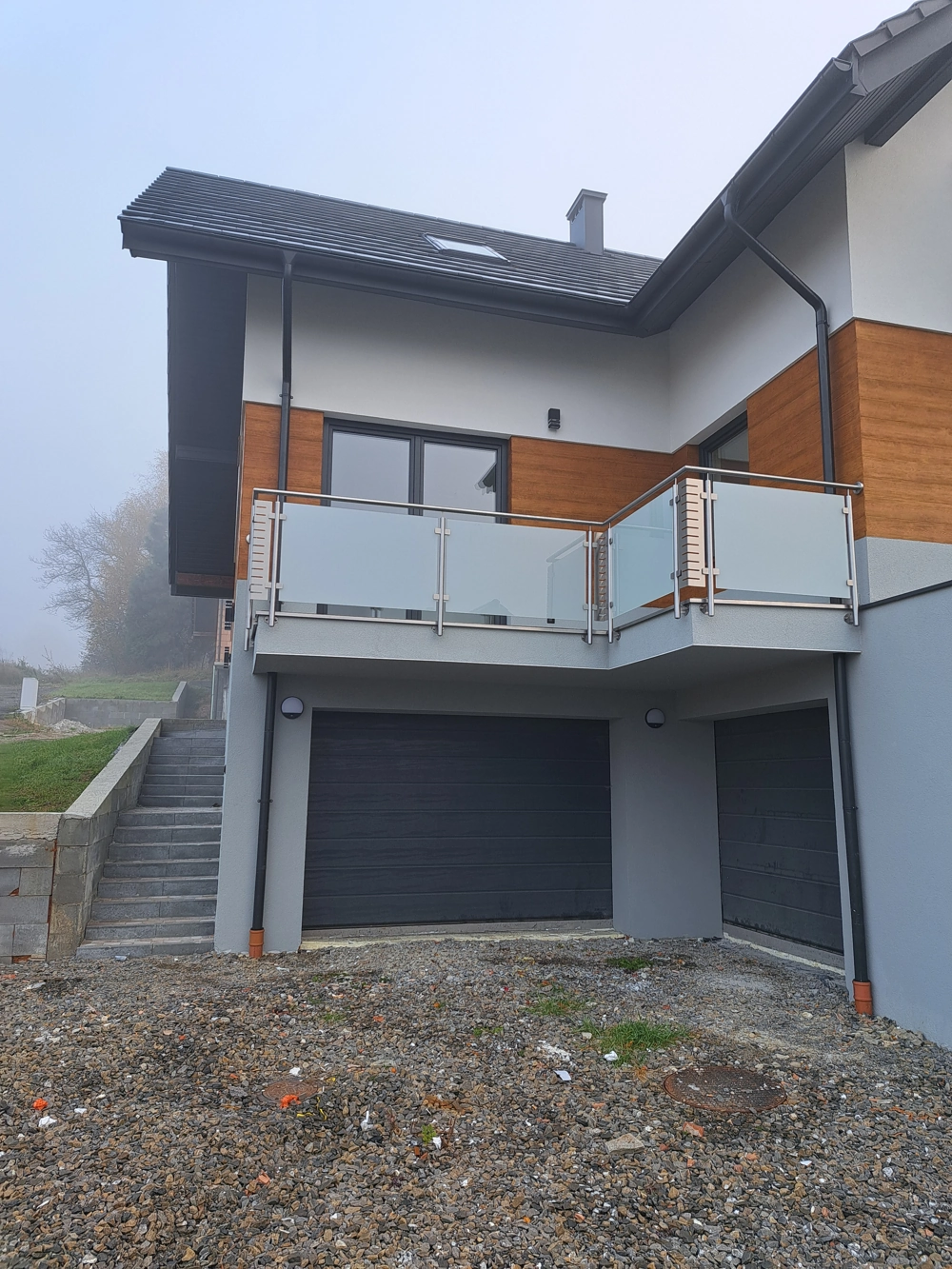 Nowoczesna szklana balustrada balkonowa na elewacji domu z garażem