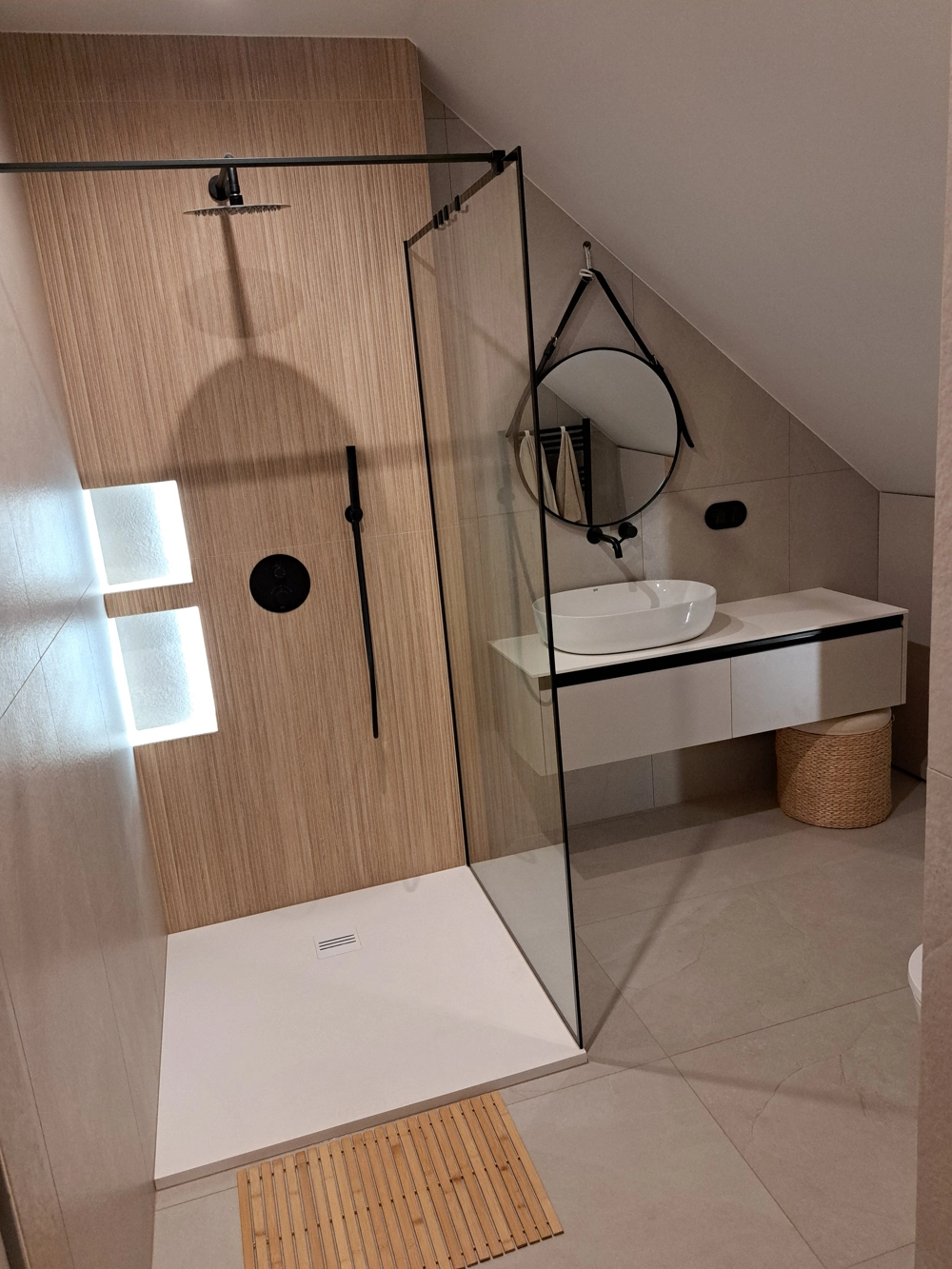 Minimalistyczna łazienka z kabiną prysznicową, szklaną ścianką, czarną armaturą i umywalką na blacie