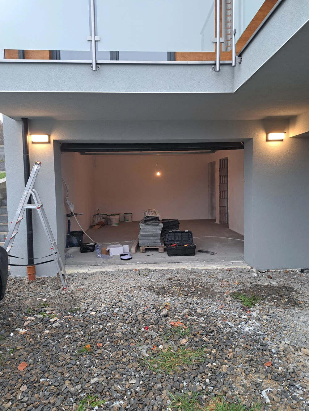 Otwarta przestrzeń garażowa z zamontowanym oświetleniem, przewodami, skrzynkami z narzędziami i materiałami budowlanymi - instalacje elektryczne