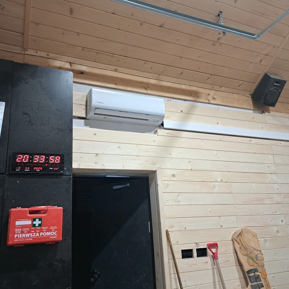 Zamontowana klimatyzacja na drewnianej ścianie z widocznym kablem w korytku