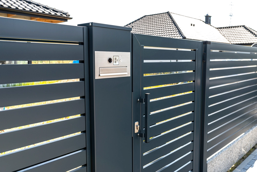 Nowoczesna brama wjazdowa z poziomymi panelami, słupek z domofonem i skrzynką na listy