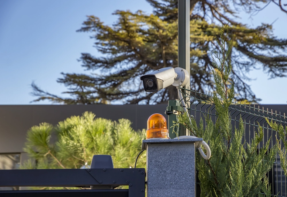 Kamera monitoringu i lampa ostrzegawcza zamontowane na ogrodzeniu panelowym